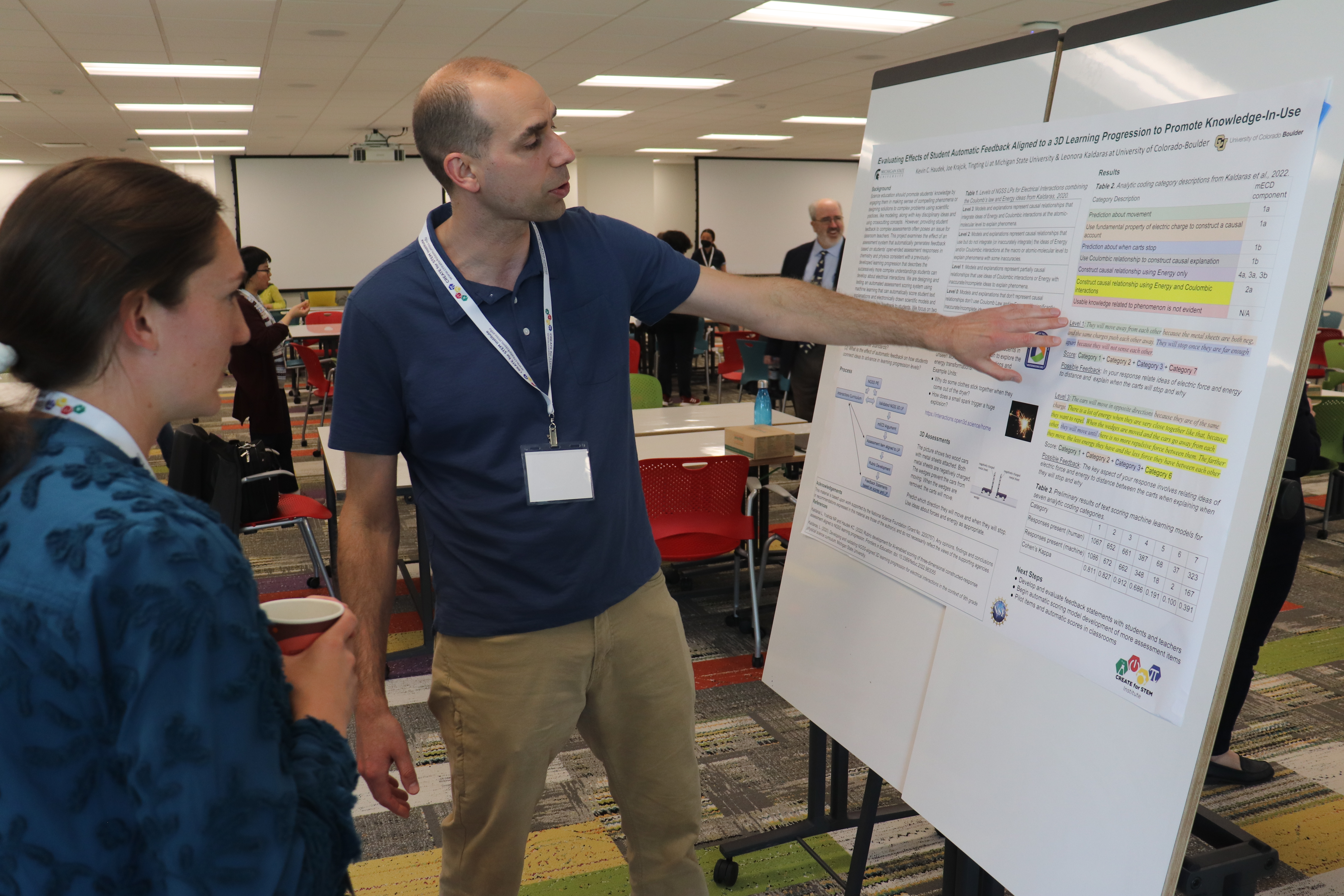 Photo of Kevin Haudek presenting poster to an attendee at Mini-Conference