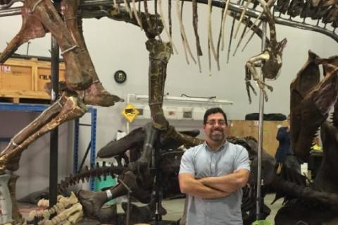 Photo of scientist in front of dinosaur skeleton